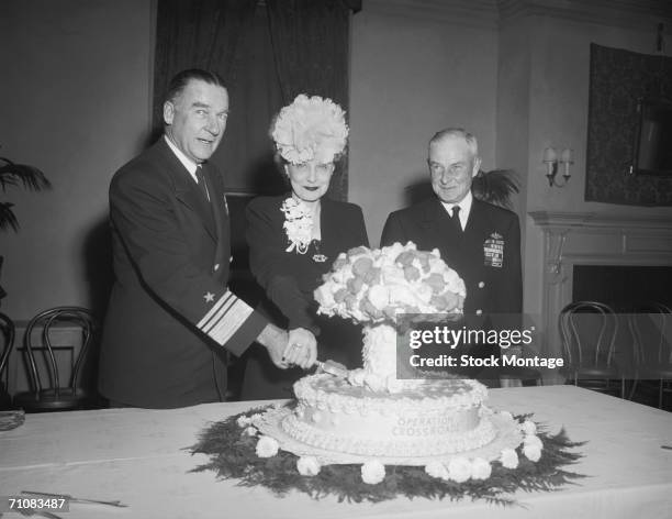 Navy Vice Admiral William H. P. Blandy , his wife, and Rear Admiral Frank J. Lowry cut a cake made in the shape of a mushroom cloud formed by the...