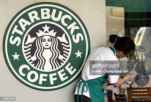 Starbucks worker cleans the window next to a company logo at a coffee store on May 31, 2006 in Seoul, South Korea. The National Tax Service has...