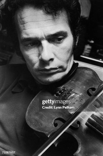 Close-up of American country music performer Merle Haggard as he plays a violin, 1970.