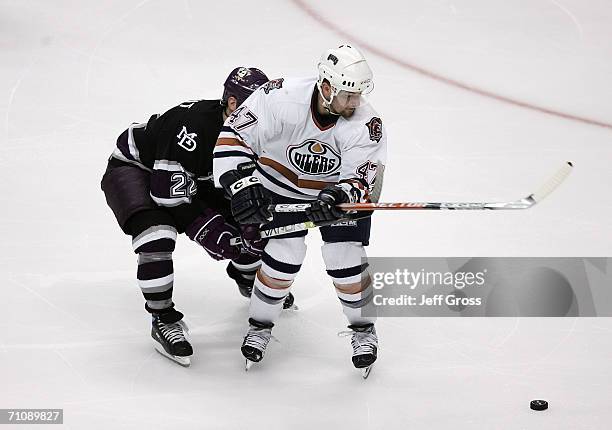 Marc-Andre Bergeron of the Edmonton Oilers looks to control the puck as Todd Marchant of the Mighty Ducks of Anaheim pursues the play during game...