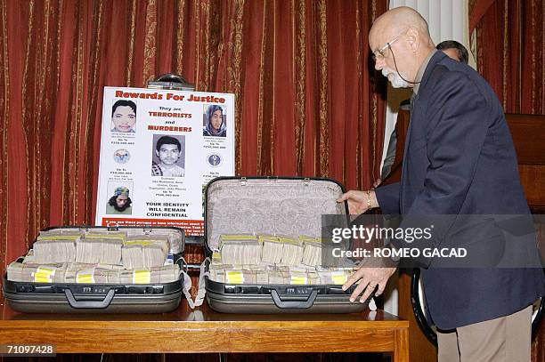 Embassy regional security officer William Lamb displays two suitcases containing the reward cash of 500,000 USD from the US Department of State's...