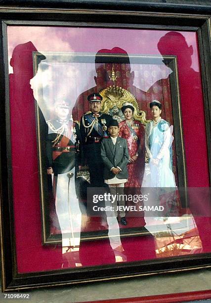 In this file picture taken 09 June 2001 in Kathmandu, Nepalese security personnels, reflected, look at a photograph of Nepalese royal family members...