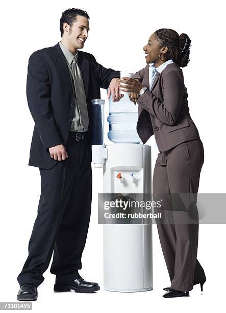 businessman and a businesswoman standing beside a water cooler - water cooler white background stock pictures, royalty-free photos & images