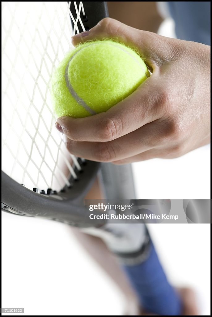 Close-up of a young woman's hand holding a tennis ball and a tennis racket