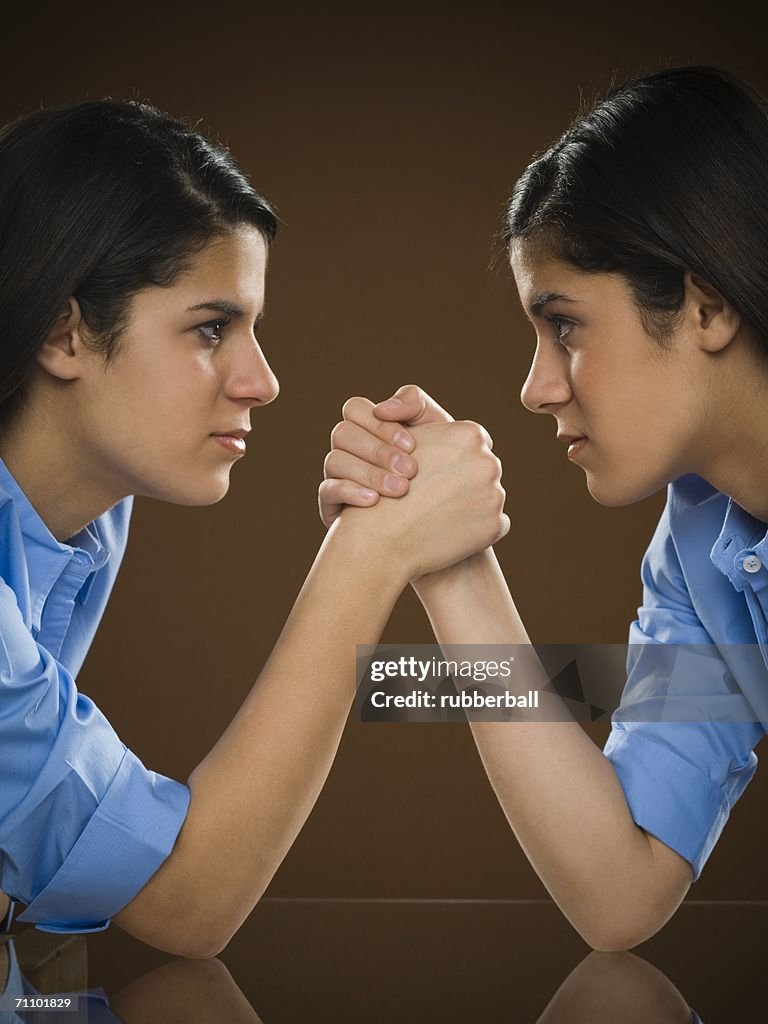 Profile of two teenage girls arm wrestling