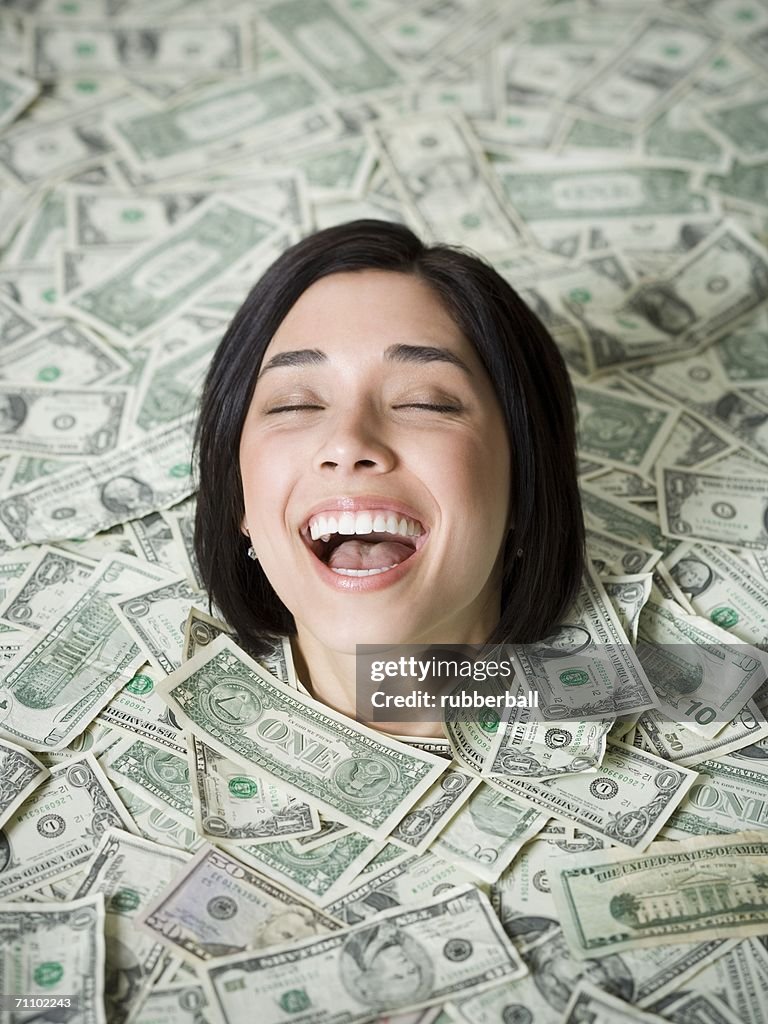 High angle view of a young woman buried under a pile of money