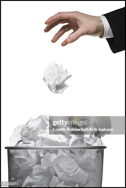 close-up of a businessman's hand throwing a paper ball into a garbage bin - paper ball stock pictures, royalty-free photos & images