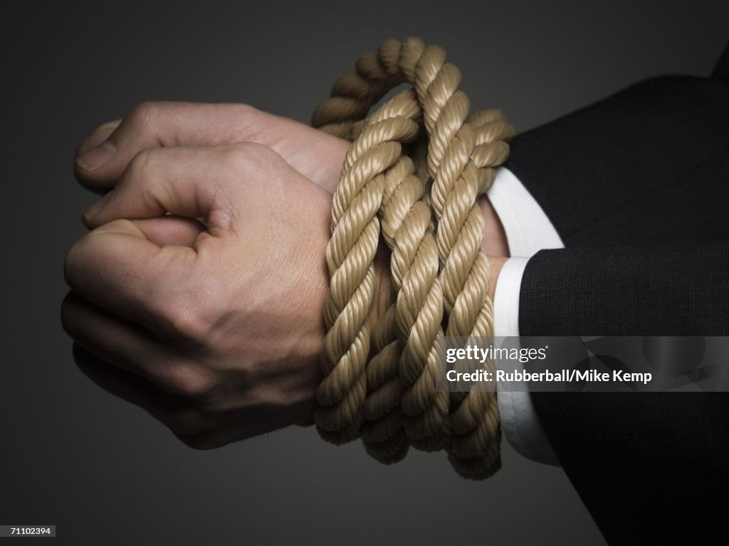 Close-up of a man's hands tied together with rope