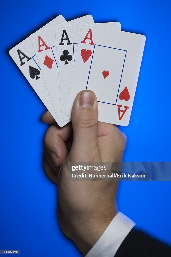 Close-up of a person's hand holding four aces