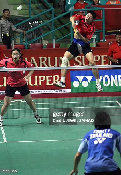 Chinese Zhonogbo Xie leaps in the air to send a smash to their Thai opponents Saralee Thoungthongkam and Sudket Prapakamol as his partner Yawen Zhang...