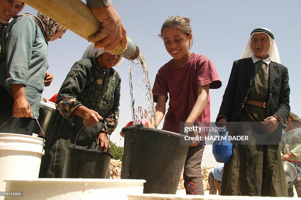 Palestinians queue holding empty buckets to be filled with water from ...