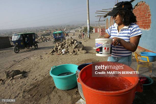 Una mujer saca agua de un recipiente por el cual pago 0.50 centavos de dolar, debido a la falta de agua potable en el asentamiento de Lomo de Corvina...