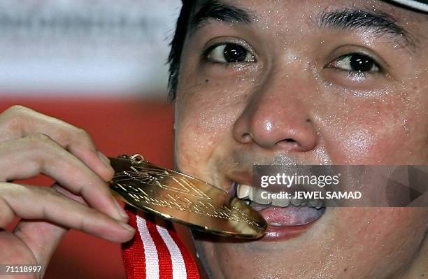 Indonesian shuttler Taufik Hidayat bites his medal after defeating his Chinese opponent Chunlai Bao during the men single final of the Indonesia Open...