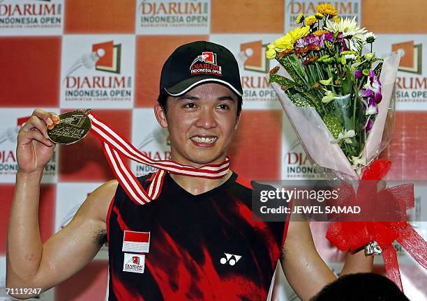 Indonesia shuttler Taufik Hidayat shows his medal after defeating Chinese opponent Chunlai Bao during the men single final of the Indonesia Open...