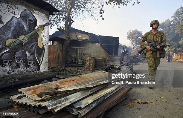Australian peacekeeping soldiers patrol through the smoke from an entire block of burning homes with Graffiti on a walls depicting death, June 5,...