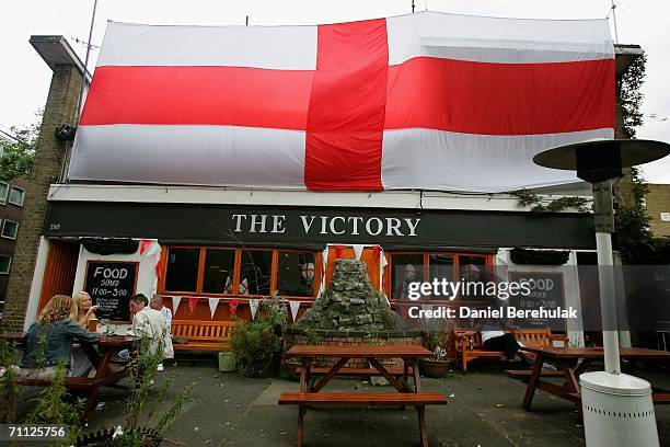 People sit in a beer garden in front of a large England flag to support the English team for the upcoming soccer World Cup in Germany on June 5, 2006...