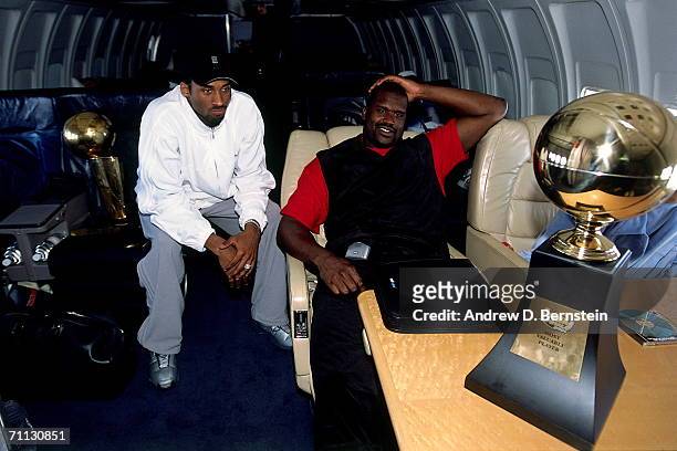 Kobe Bryant and Shaquille O'Neal of the Los Angeles Lakers chat on board the Lakers' team flight back to Los Angeles the day after defeating the...