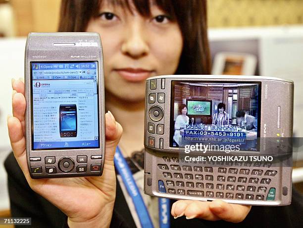 Japan's mobile communication operator Willcom's employee Kyoko Hasegawa displays a new model of a PDA shaped cellular phone "W-Zero3", equipped with...