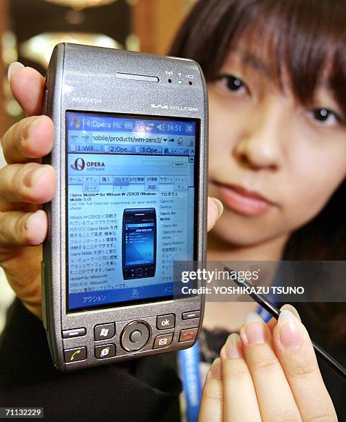 Japan's mobile communication operator Willcom employee Kyoko Hasegawa displays the new model of PDA shaped cellular phone "W-Zero3", equipped with...