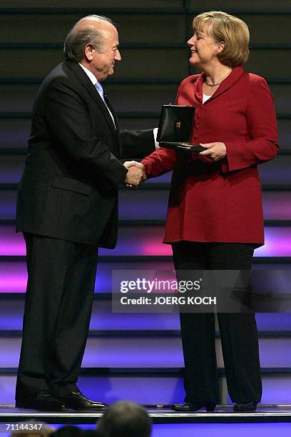 President Sepp Blatter presents a golden medal to German Chancellor Angela Merkel 07 June 2006 in Munich after the opening of a two-day congress of...
