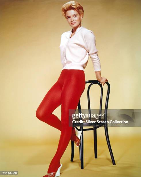 American actress Angie Dickinson wearing a white cardigan and red tights, circa 1955.