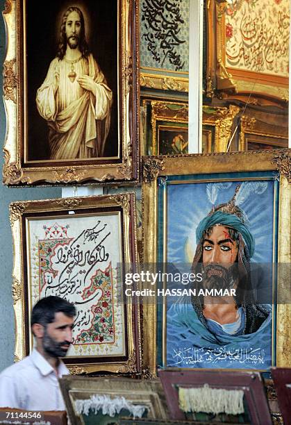 An Iranian man walks next to a portrait of Abu Al-Fadl Al-Abbas, the son of revered Imam Ali who was killed in Karbala, hanged near to another...