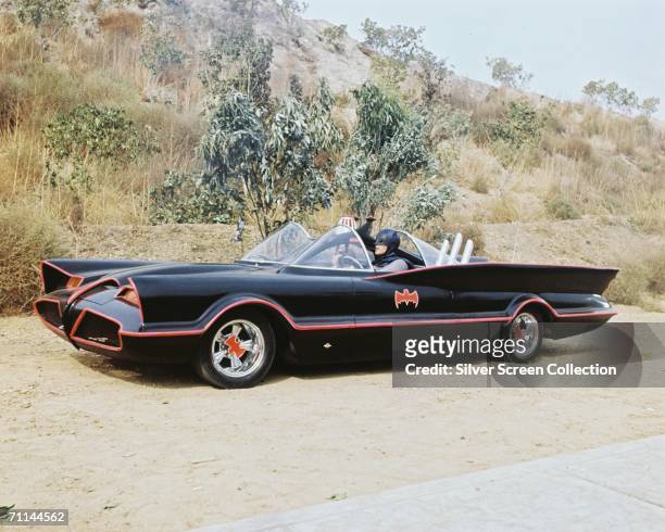 American actor Adam West as Bruce Wayne/Batman at the wheel of the Batmobile with passenger Burt Ward as Dick Grayson/Robin in the TV series...