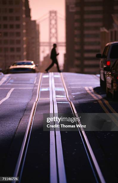 pedestrian crossing cable car tracks on nob hill with bay bridge in background, san francisco, united states of america - nob hill stock pictures, royalty-free photos & images