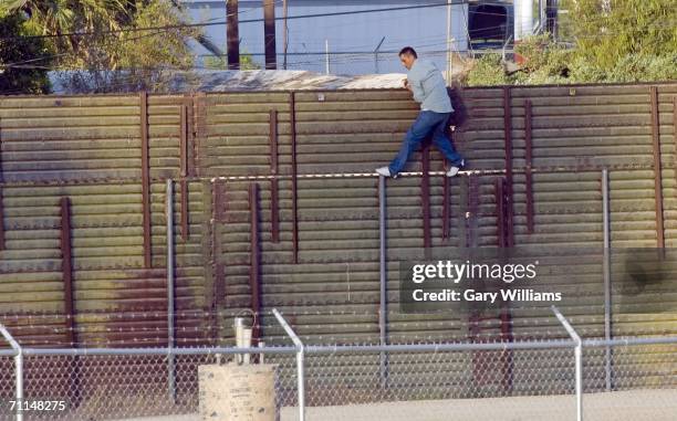 Man walks along the U.S. Side of the 15-foot high border fence toward a Border Patrol agent in a truck after scaling the barrier from Mexico June 7,...