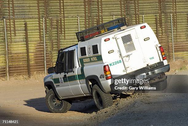 Border Patrol agent goes after an illegal immigrant as he tries to climb over a 15-foot high border fence with Mexico June 7, 2006 in San Luis,...