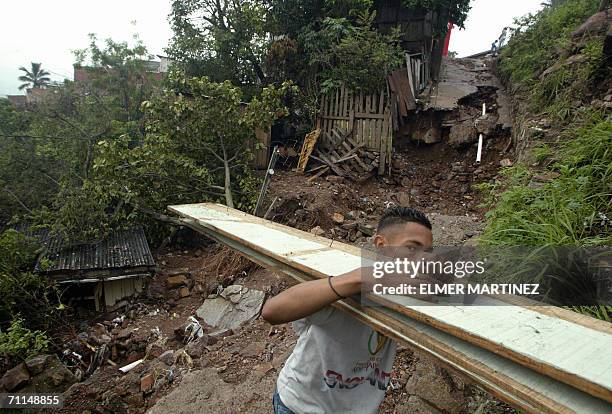 Tegucigalpa, HONDURAS: Un habitante de la colonia Villa Union de Tegucigalpa, carga tablas de madera con las que estaba construida su casa, tras...