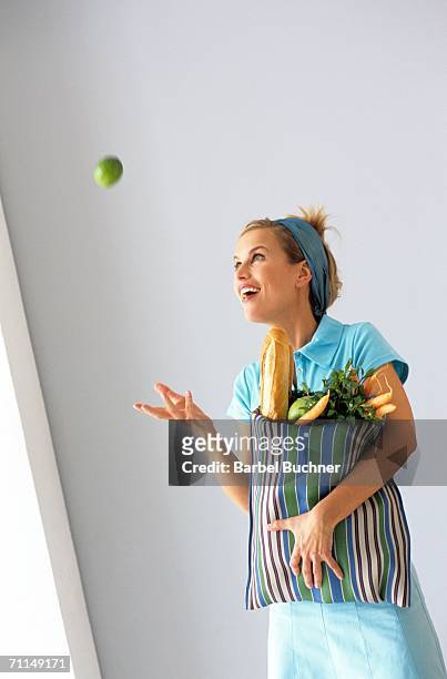 woman with shopping bag throwing apple in air - throwing food stock pictures, royalty-free photos & images