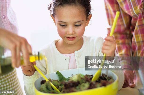 parents with daughter preparing salad - family with one child mother bonding family adult daughter focus on background leisure stock-fotos und bilder