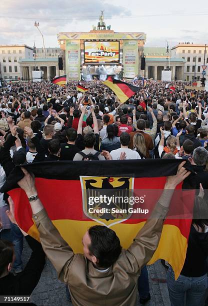 Man waves a German flag among fans gathered for the opening party of the FIFA World Cup 2006 in the Fan Fest in front of the Brandenburg Gate June 7,...