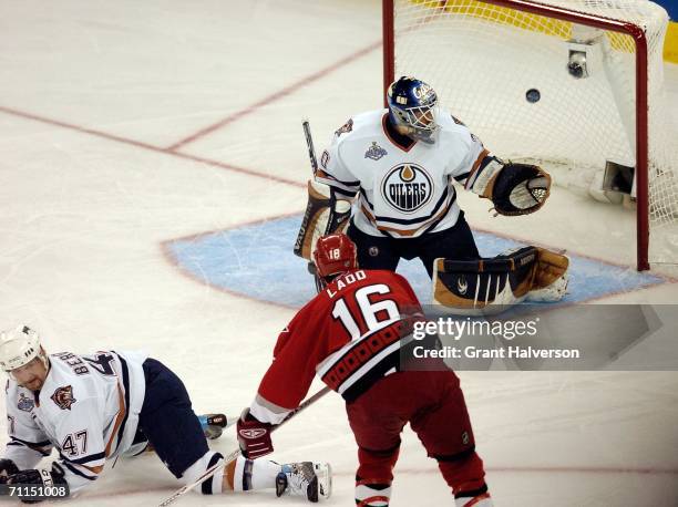 Andrew Ladd of the Carolina Hurricanes scores the first goal over goaltender Jussi Markkanen and Marc-Andre Bergeron of the Edmonton Oiler during the...