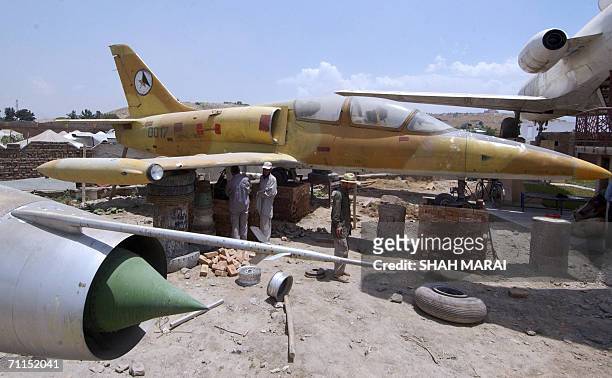 Afghan workers stand by a Soviet-era fighter jet that is among the newest additions to a collection of war aircrafts on display at the demining...