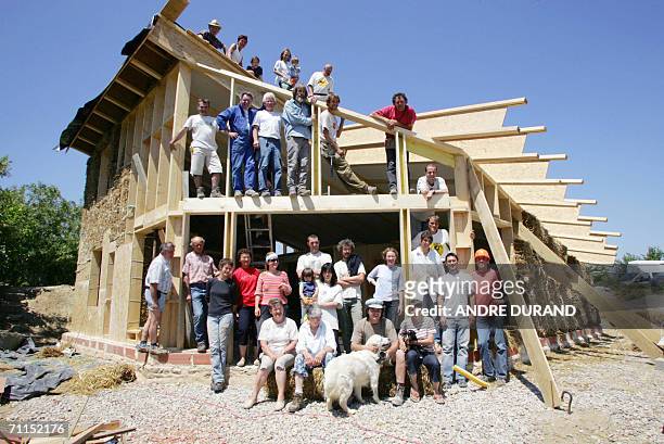 Les benevoles de l'association terre de vent posent le 07 juin 2006 a Athee devant la maison bioclimatique qu'ils fabriquent a partir de paille, de...