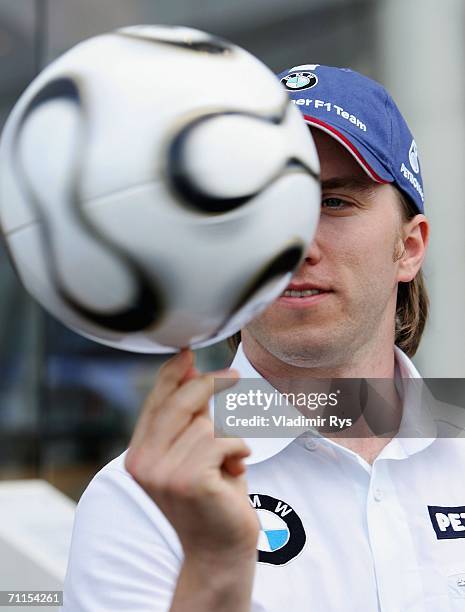 Nick Heidfeld of Germany and BMW Sauber plays with the Teamgeist Wolrd Cup ball in the paddock during the preparations for the Formula One British...