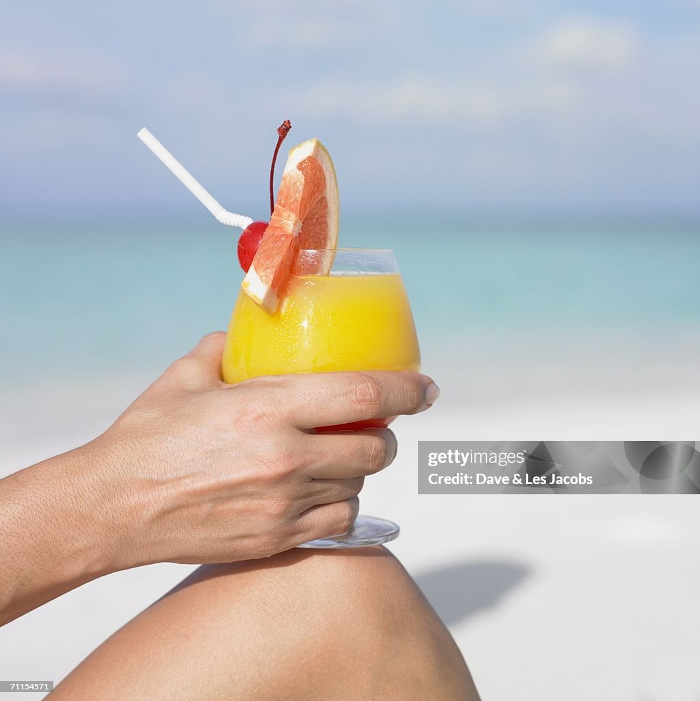 Woman holding a tropical drink at the beach