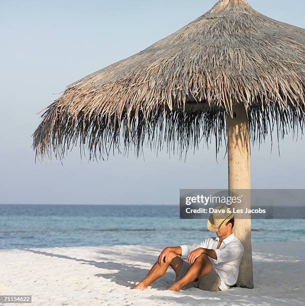 young man asleep at the beach - beach shelter ストックフォトと画像