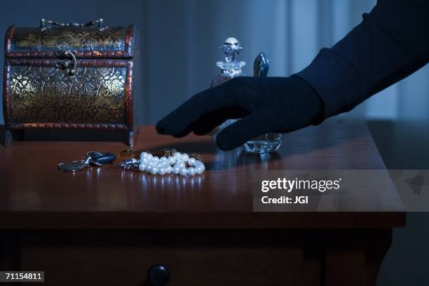 thief reaching for a string of pearls - up on a roof stockfoto's en -beelden