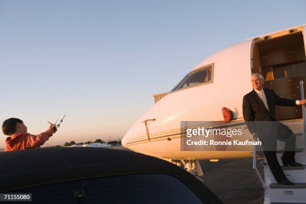 businessman greeting son from plane - private jet stock-fotos und bilder