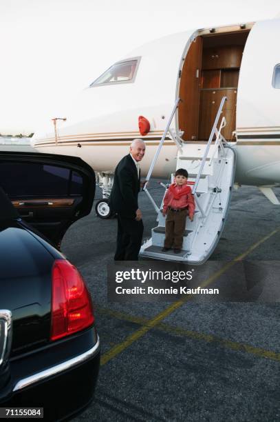 businessman and young boy on airplane runway - private jet stock-fotos und bilder