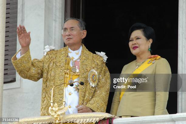 Thailand's King Bhumibol Adulyadej and Queen Sirikit wave to the thousands of people waiting outside the Royal Plaza to pay tribute to King Bhumibol...