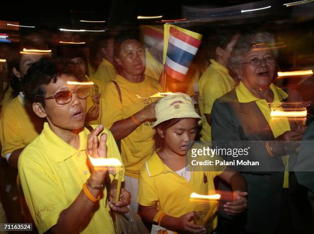 Thai people hold candles and sing the national anthem at Sanam Luang grounds as part of a ceremony to pay homage to Thailand's King Bhumibol...