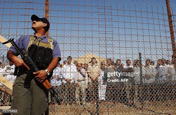 Iraqi prisoners wait to be released as a security guard of Iraqi Vice President is seen 11 June 2006 at Abu Ghraib prison west of Baghdad. Iraq...