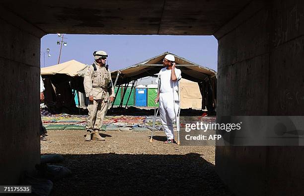Soldier stands guard near a handicapped Iraqi prisoner before his release 11 June 2006 at Abu Ghraib prison west of Baghdad. Iraq released 230...