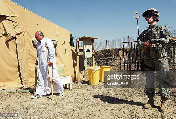 Soldier stands guard near a handicapped Iraqi prisoner before his release 11 June 2006 at Abu Ghraib prison west of Baghdad. Iraq released 230...
