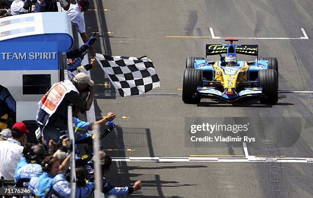 Fernando Alonso of Spain and Renault crosses the finish line first during the British F1 Grand Prix at Silverstone Circuit on June 11, 2006 in...