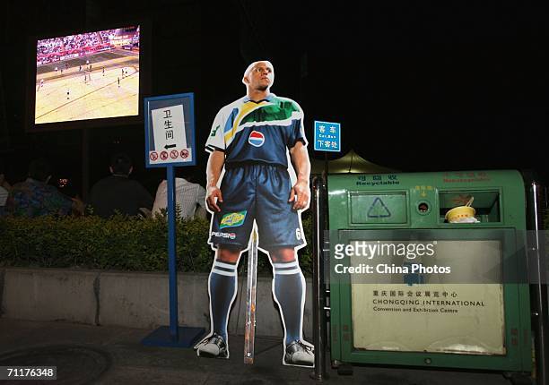 Portrait of Brazil football player Roberto Carlos stands near a trash bin as people enjoy live broadcast World Cup games through screen in front of...